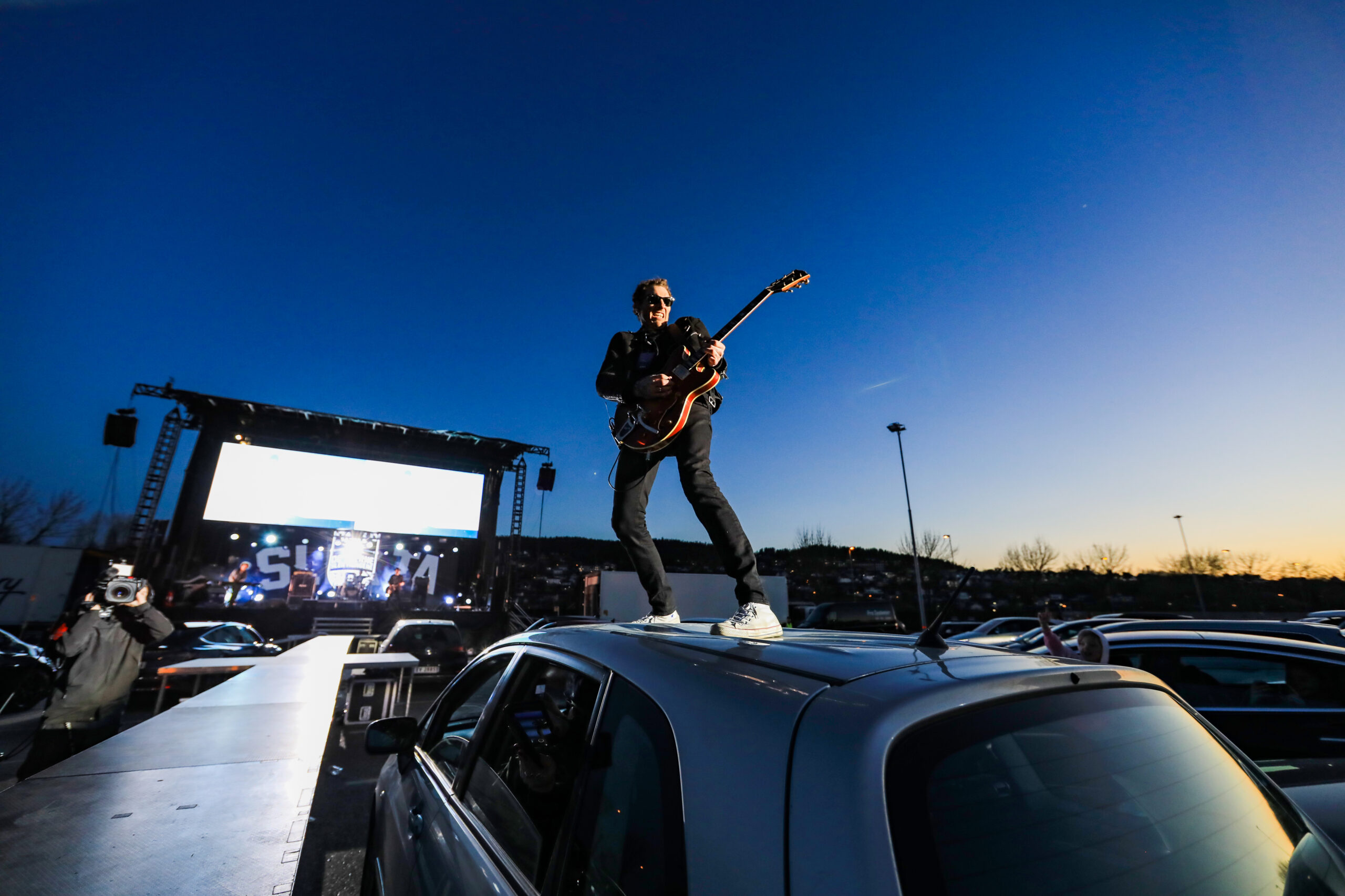 Un guitarrista en el techo de un auto.